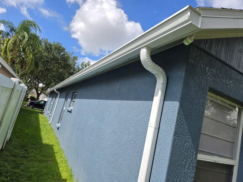 White seamless gutters installed across a blue two-story Florida home