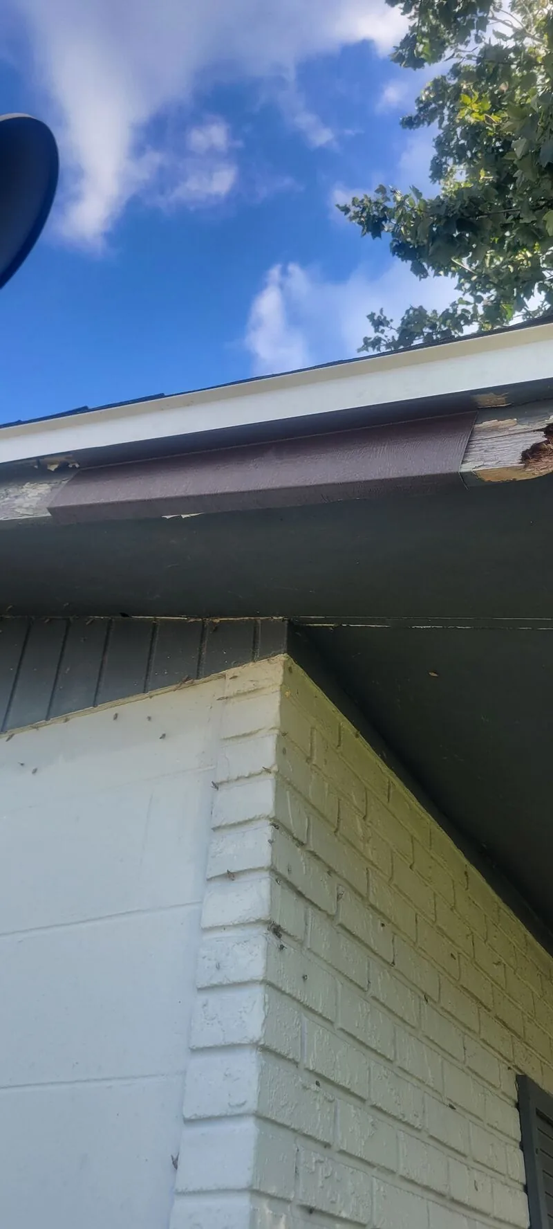 Repaired fascia and soffit corner on a white brick home