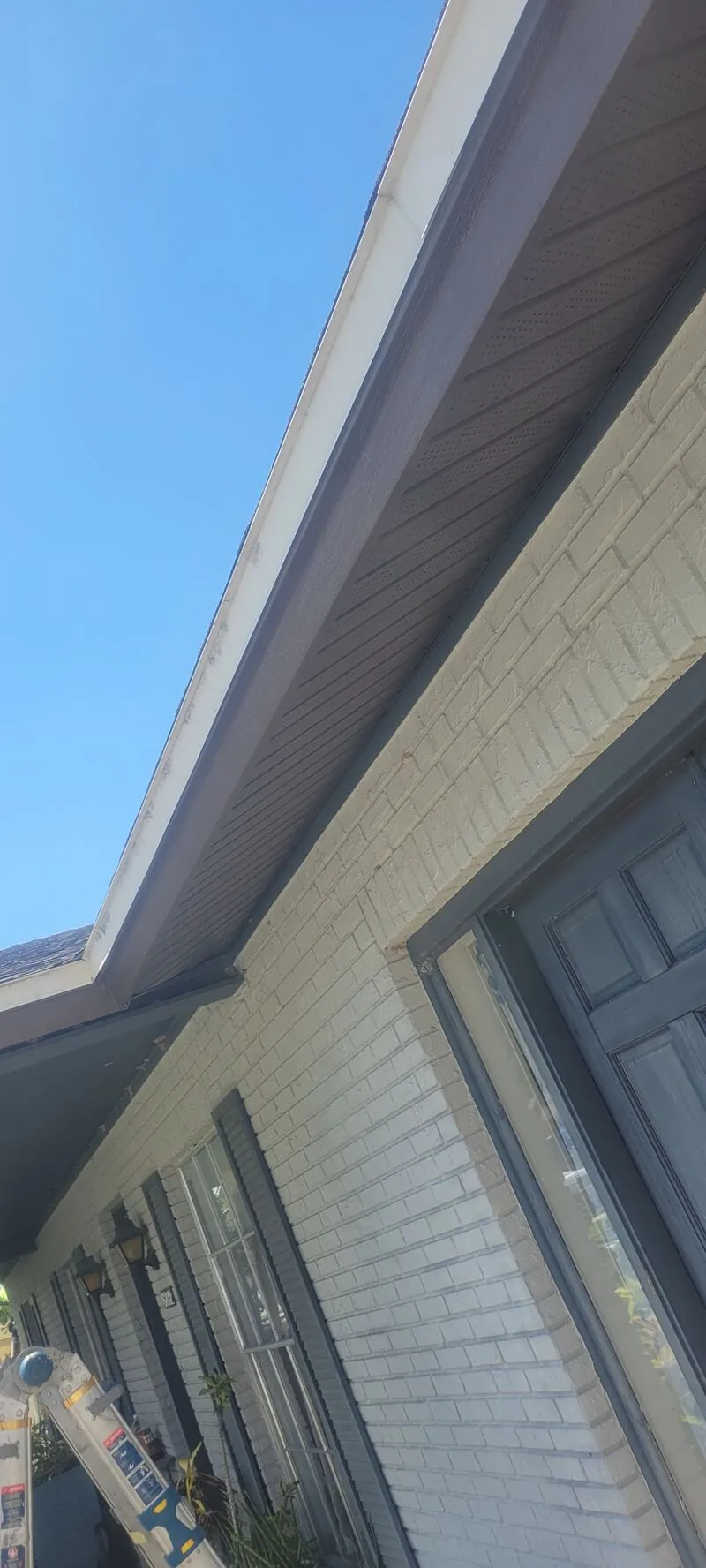 New fascia wrap running the roofline of a white brick house