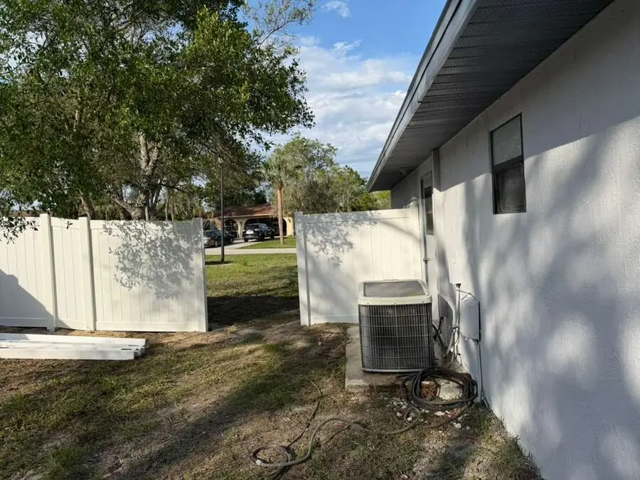 White vinyl privacy fence installed along a wooded backyard property line