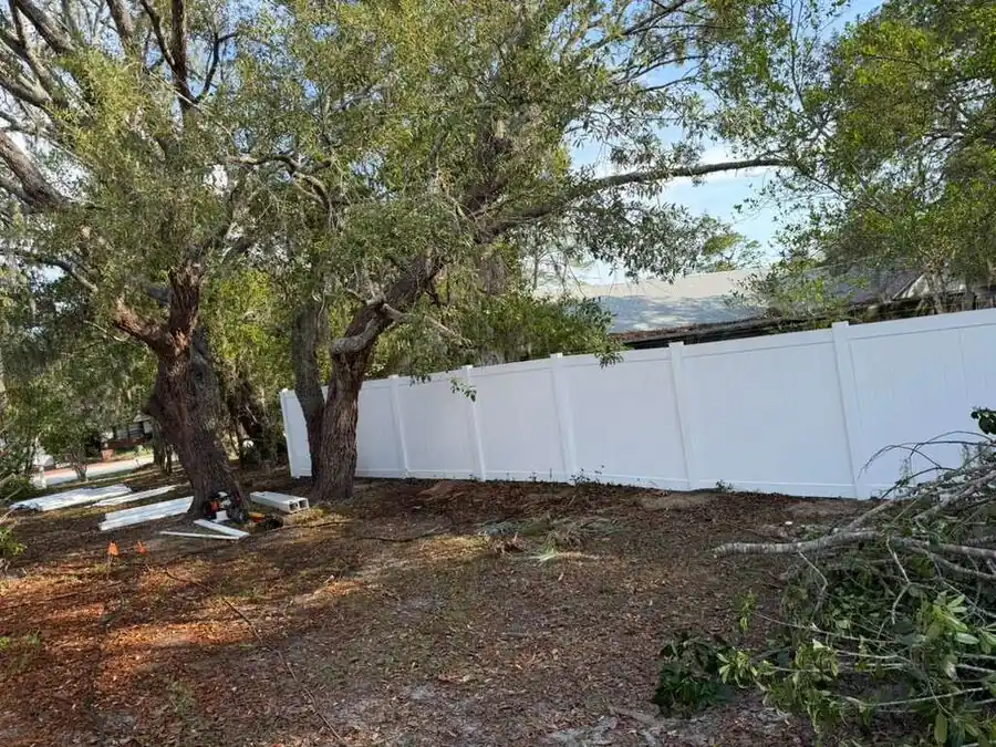Long run of white vinyl privacy fence following a property boundary
