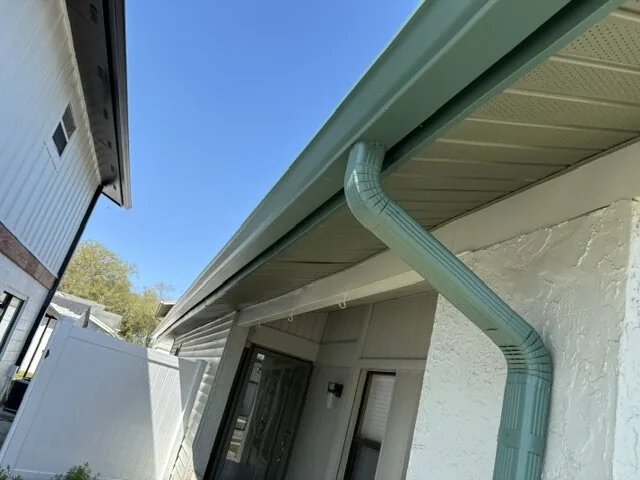 Green 7-inch seamless gutter with downspout freshly installed