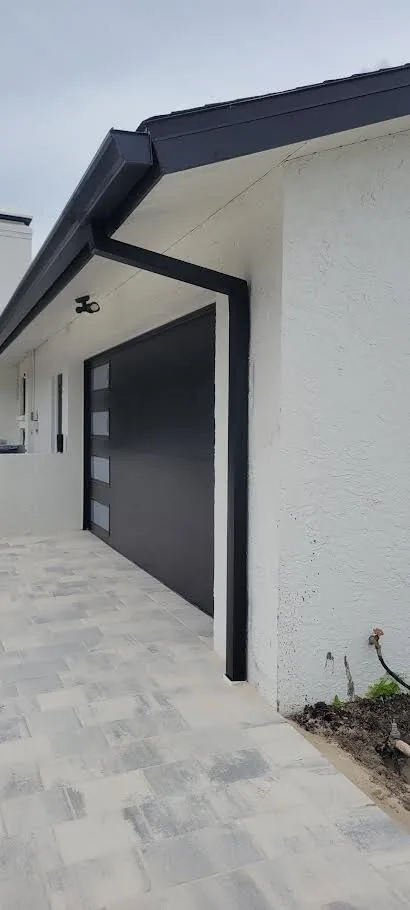 Black K-style gutters with square downspouts on a modern white home